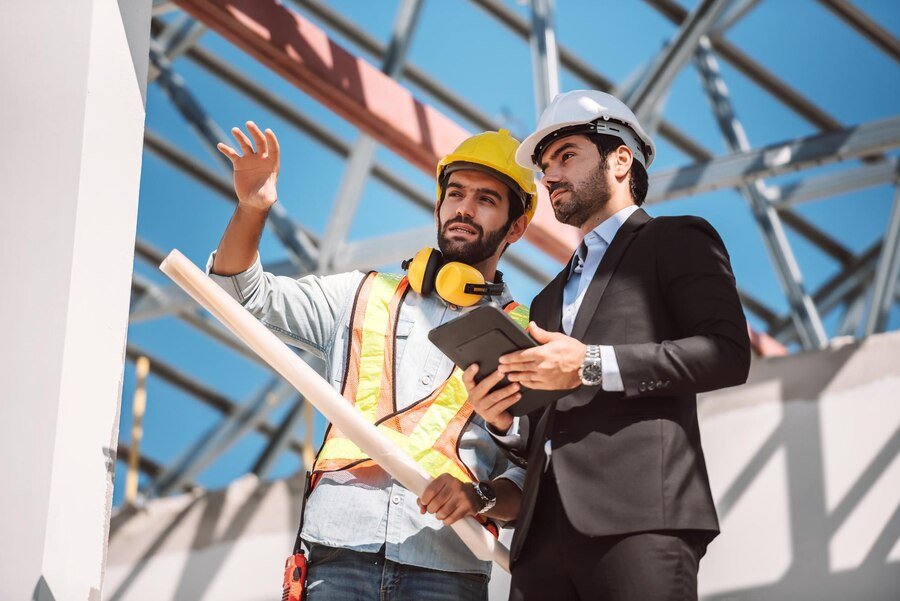 civil-engineer-construction-worker-manager-holding-digital-tablet-blueprints-talking-planing-about-construction-site-cooperation-teamwork-concept_640221-298